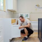 Parent installing cabinet safety locks in a kitchen to childproof the home.