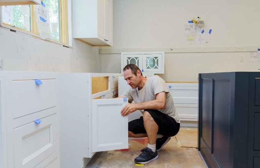 Parent installing cabinet safety locks in a kitchen to childproof the home.