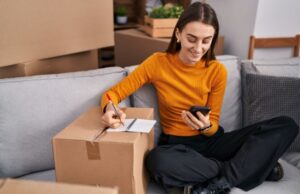 Homeowner creating a home inventory checklist using a smartphone and notebook.