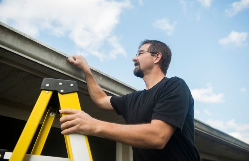 Homeowner inspecting gutters and roof as part of routine home maintenance.